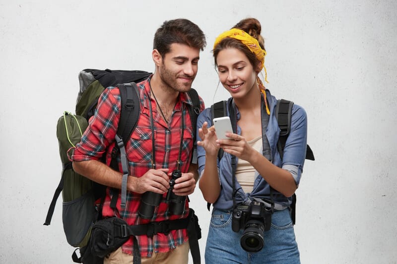 Happy young tourists looking at a phone